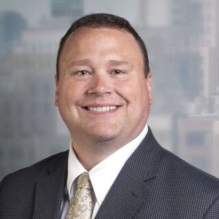 Photo of a smiling Michael Buratowski wearing a suit. Buratowski is the Senior Director of Cybersecurity Operations for The Home Depot and is the keynote speaker for FloCon 2025